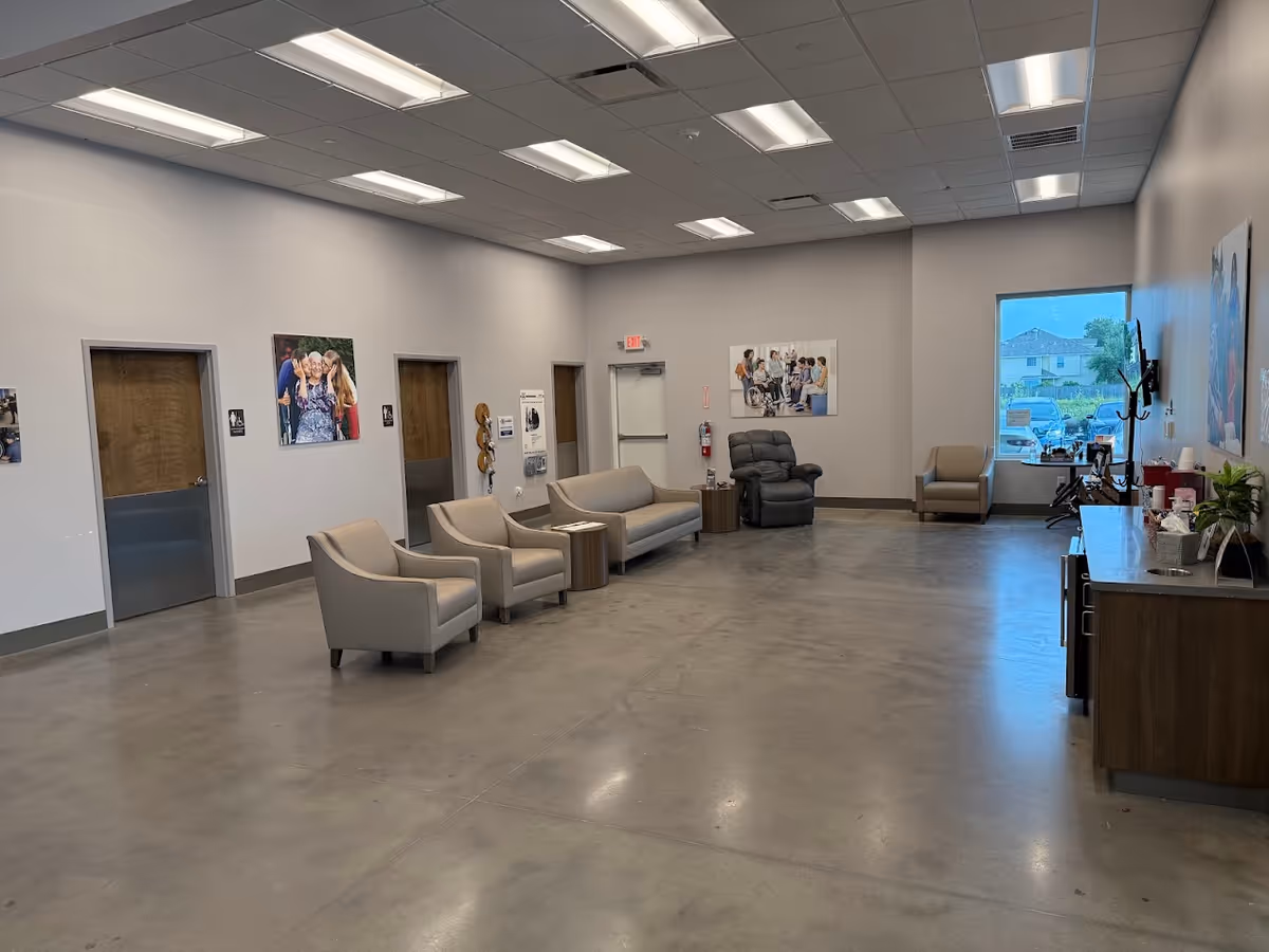 Senior living facility lobby with multiple chairs, sofas, a recliner, and a front desk.