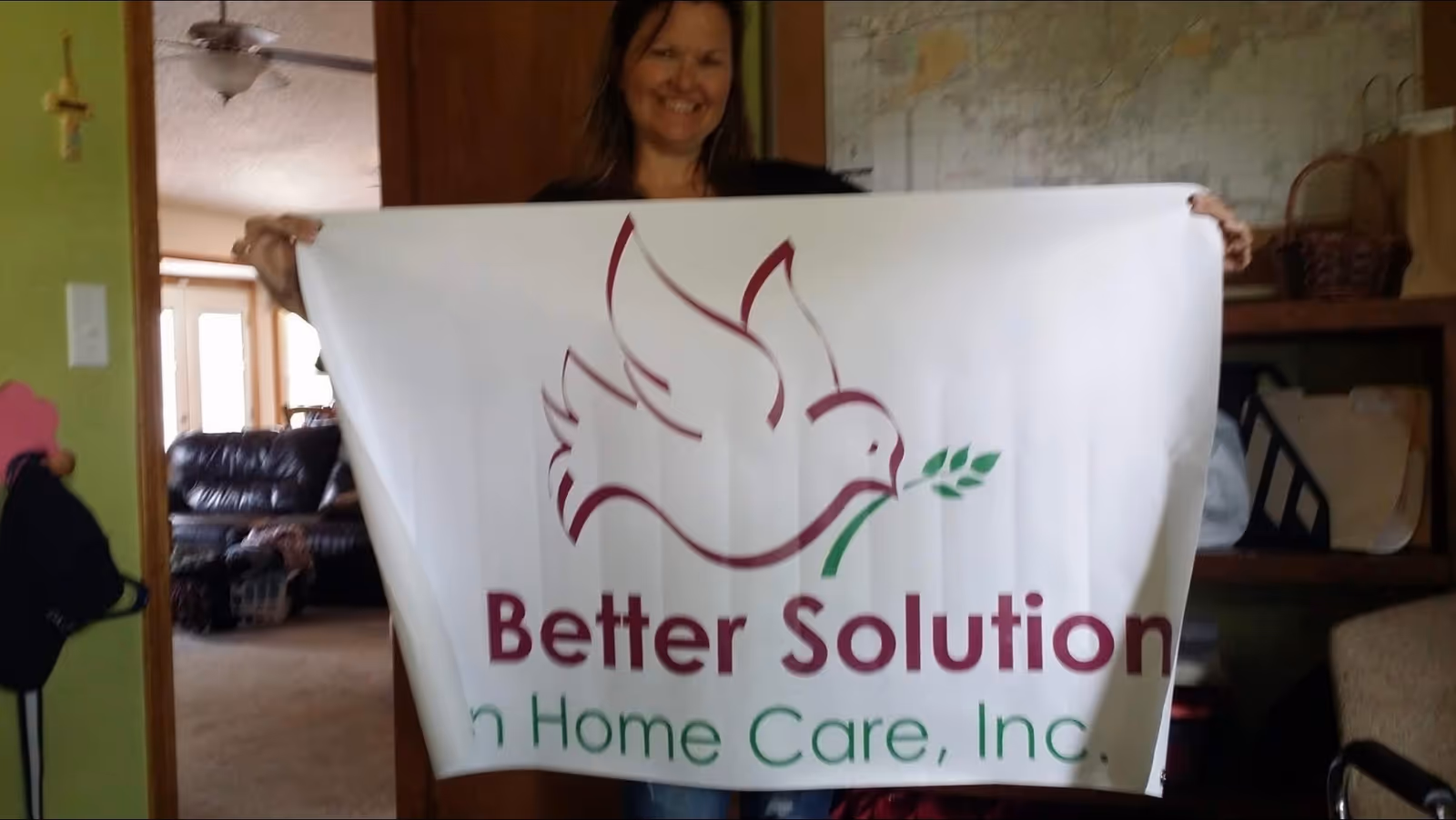 Person holds a large banner reading Better Solution In Home Care, Inc. in a living room
