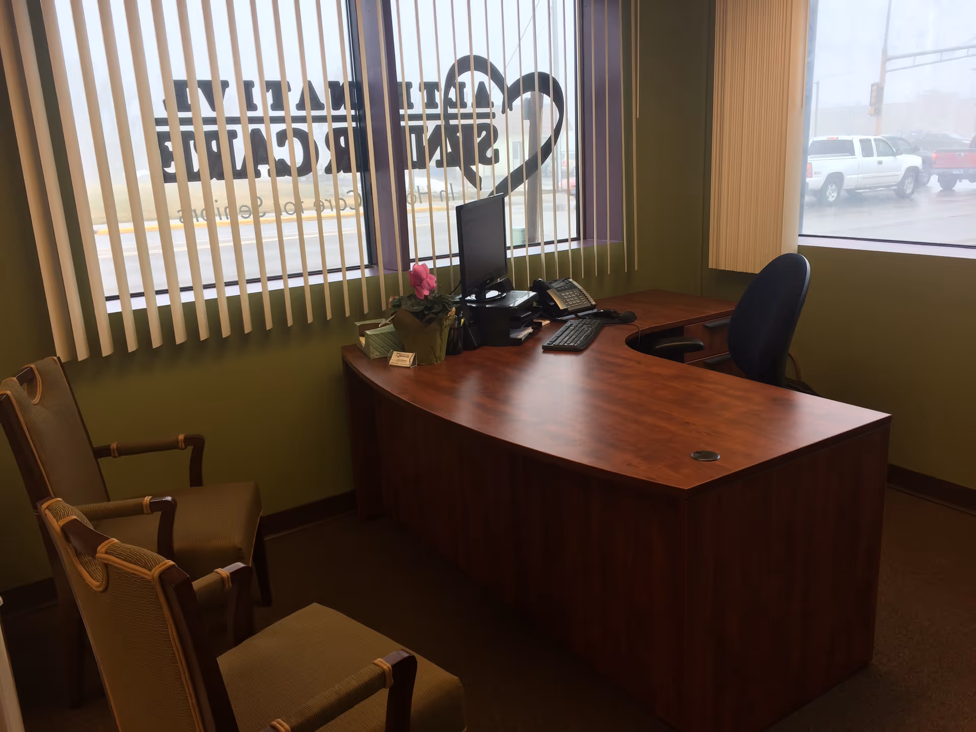 Reception desk with computer and chairs in a green interior office area.