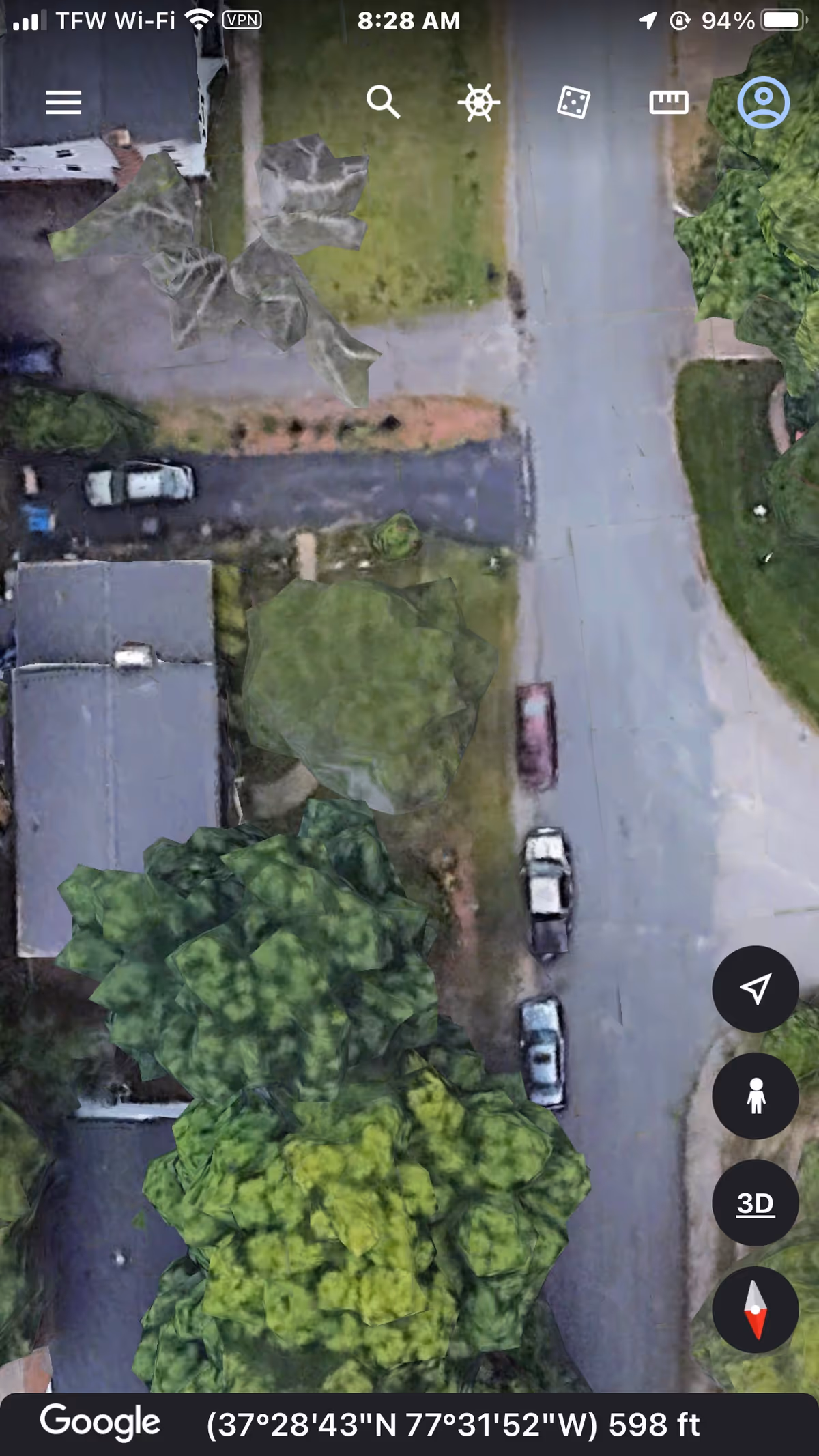 Aerial exterior view of a building with trees and parked cars along a street.