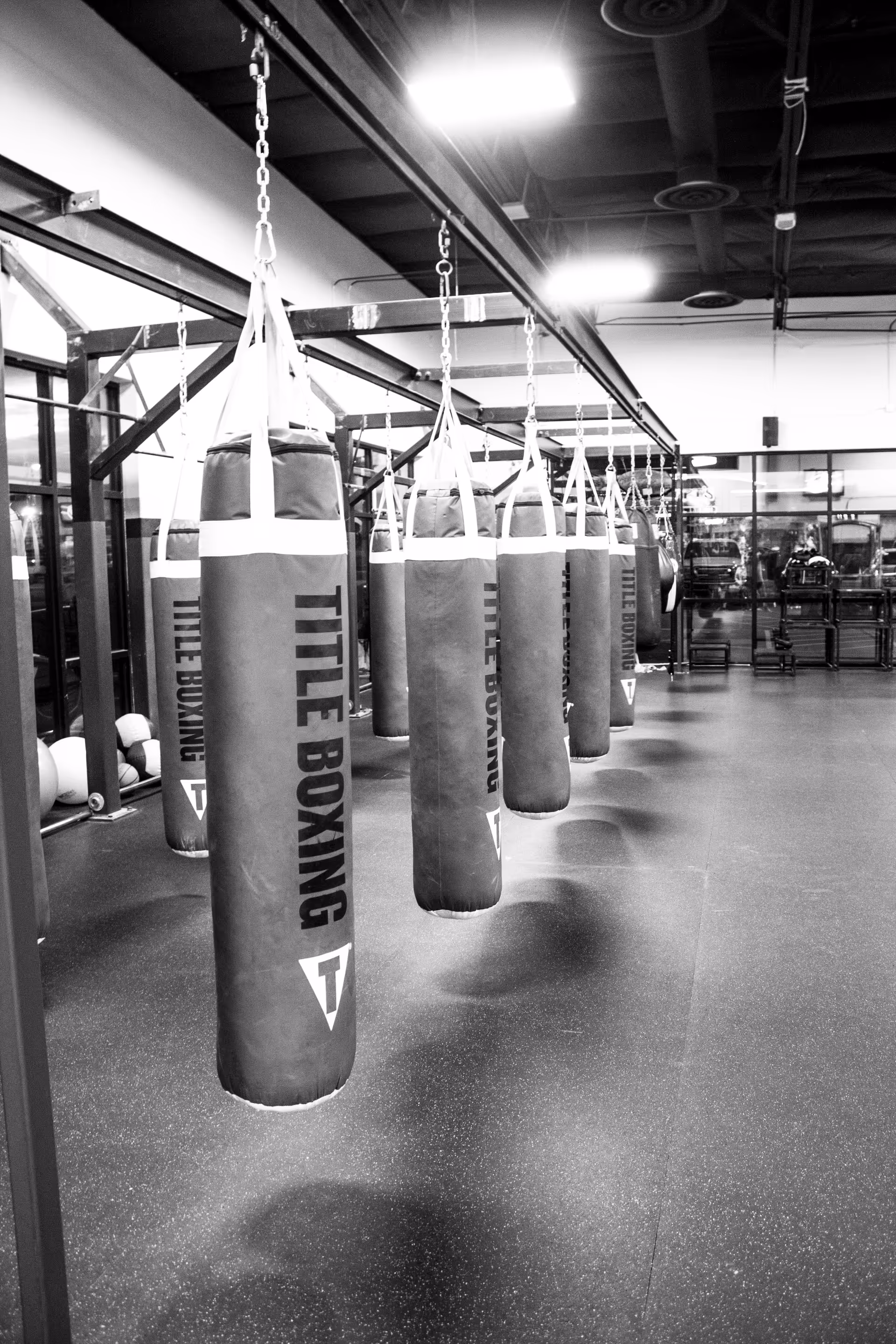 Row of hanging punching bags in a modern indoor gym area.