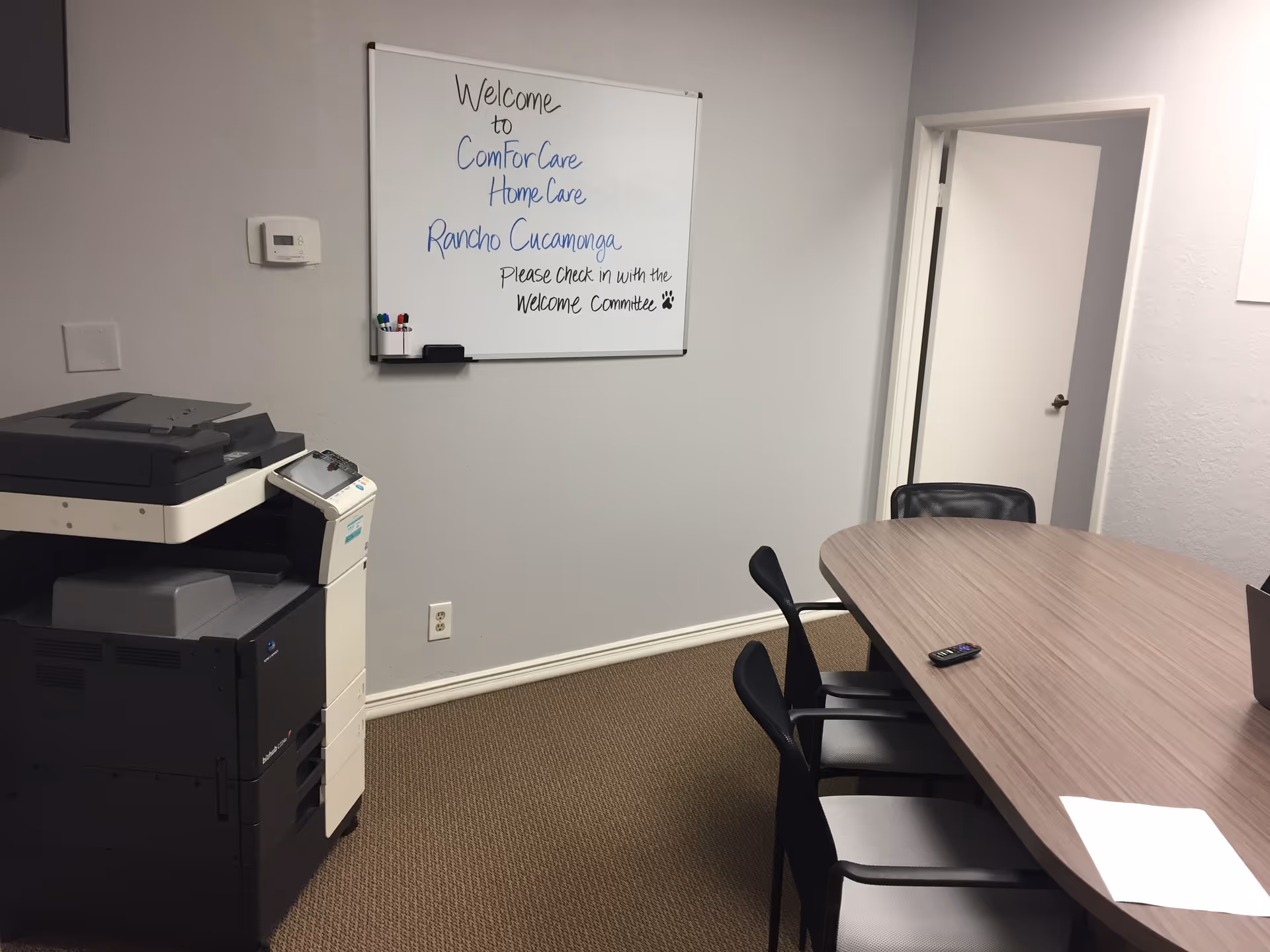 Empty conference room with copier, whiteboard, and a table with chairs.