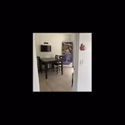 Small dining area with table, chairs, wall-mounted TV, and a poster stand.