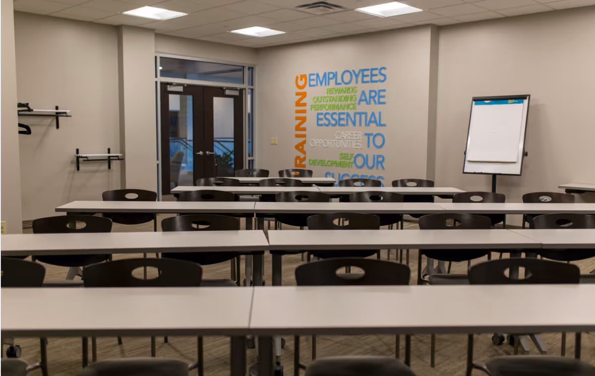 Training room with rows of tables and chairs and a colorful word mural on the wall.