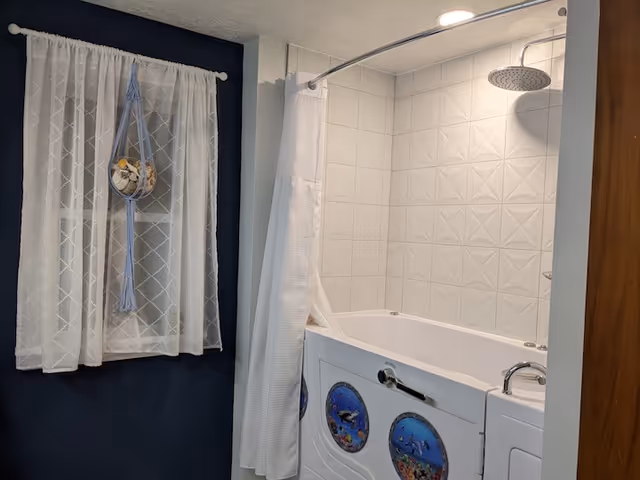 Bathroom featuring a walk-in tub, white tiled shower, curved shower rod, lace window curtain.
