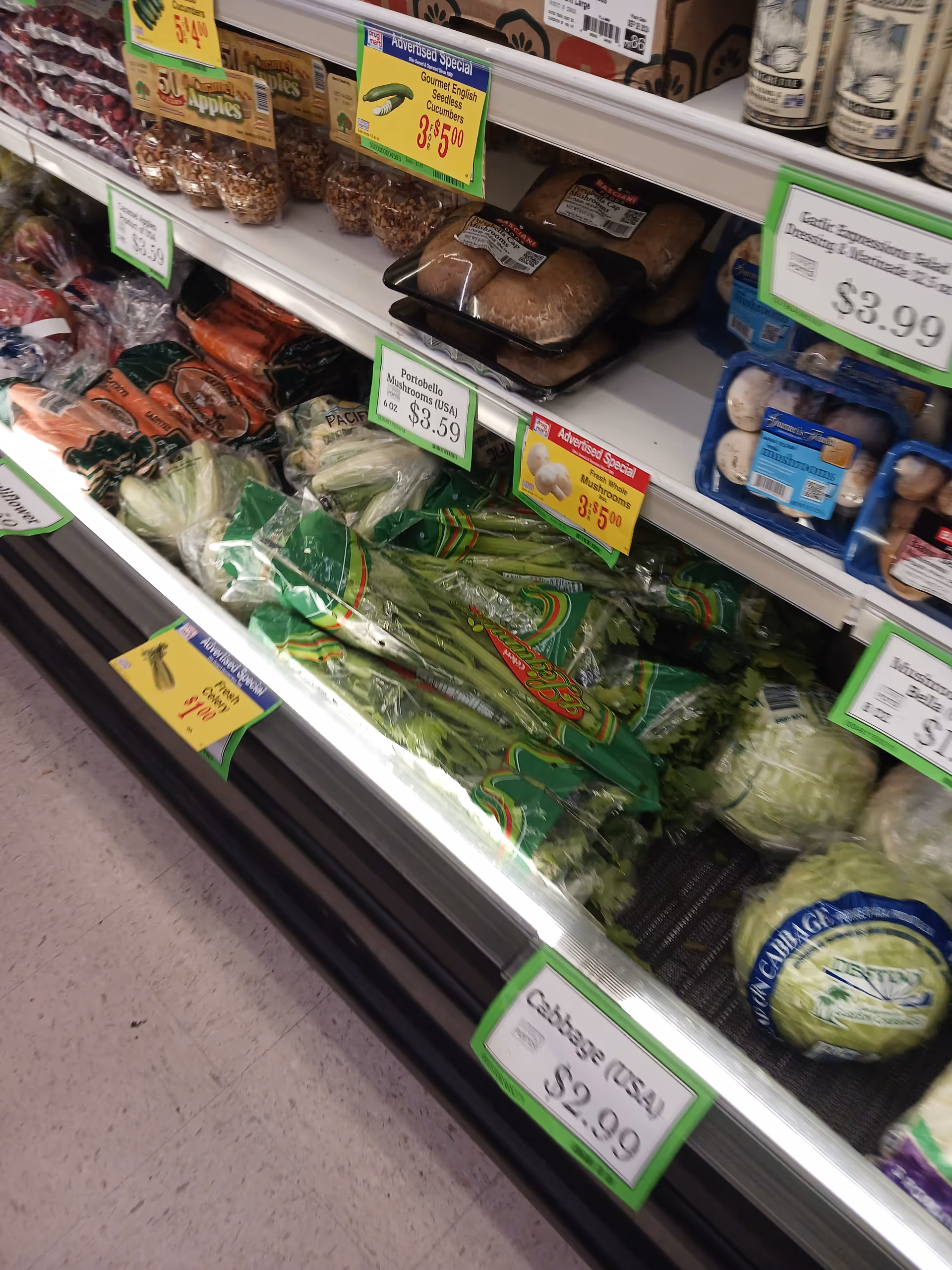 A grocery store aisle filled with vegetables and price-tag signage.