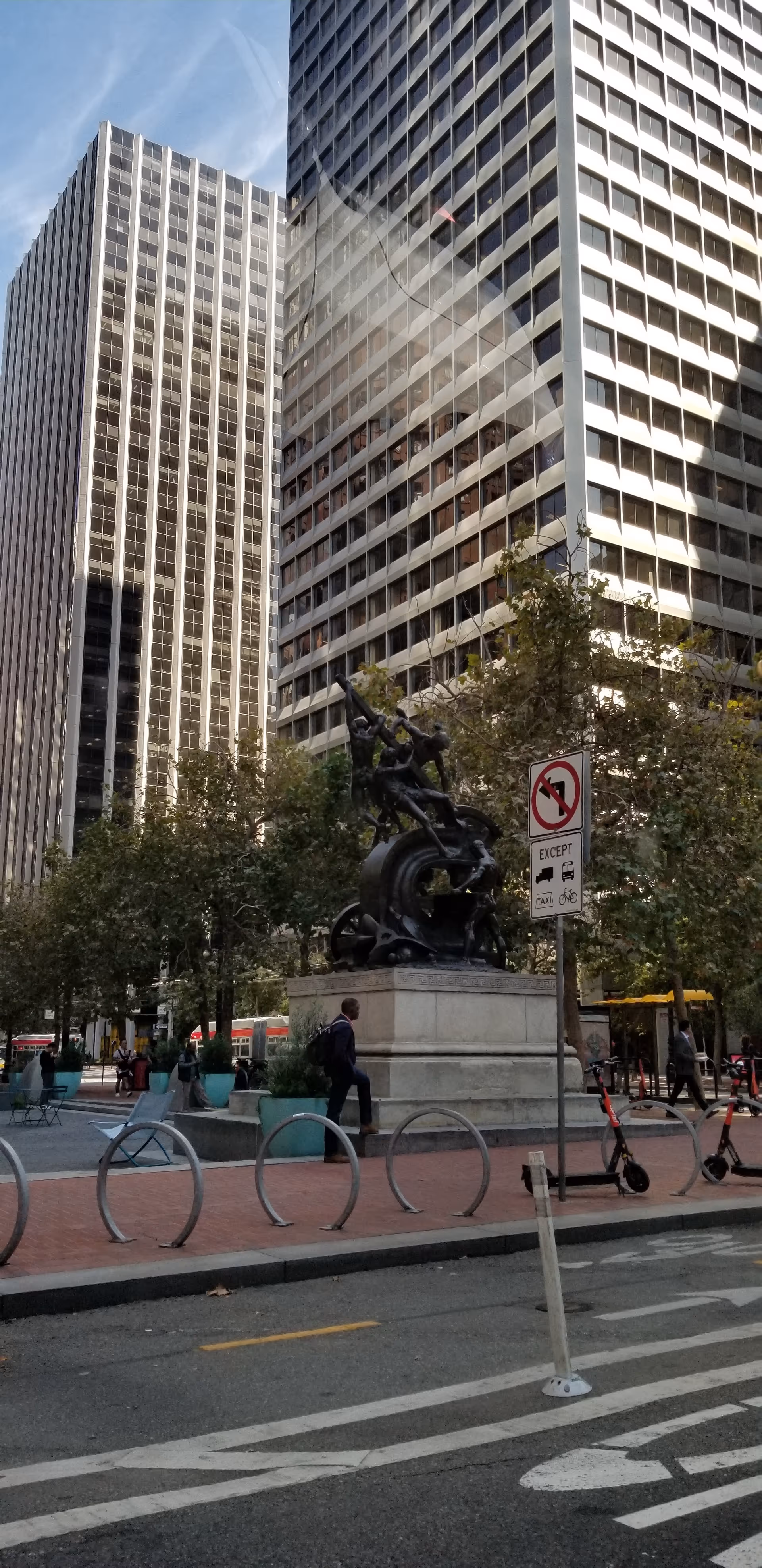 City plaza with a statue and tall office buildings under a clear blue sky