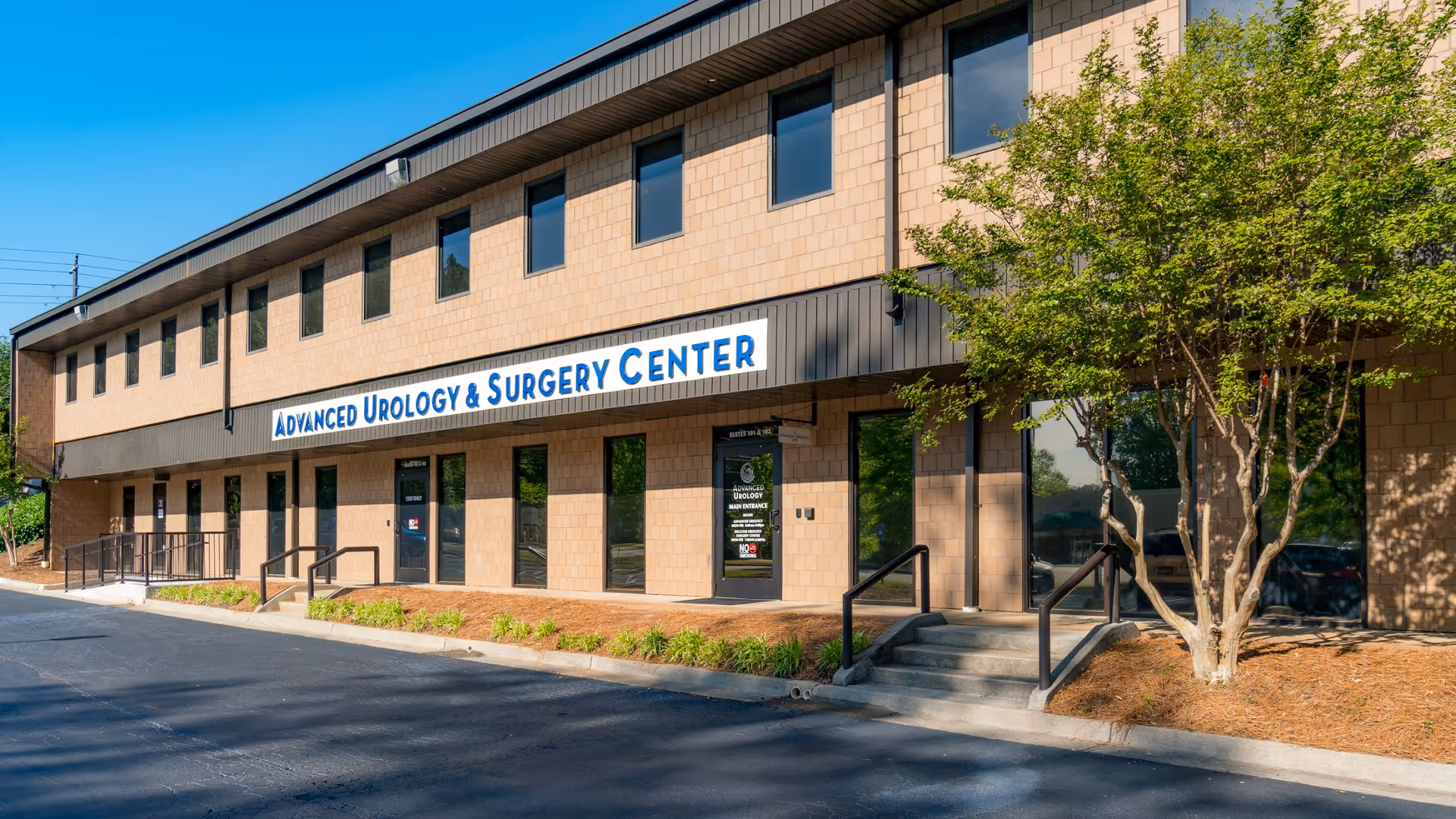 Exterior view of Advanced Urology & Surgery Center storefront with sidewalk and trees.
