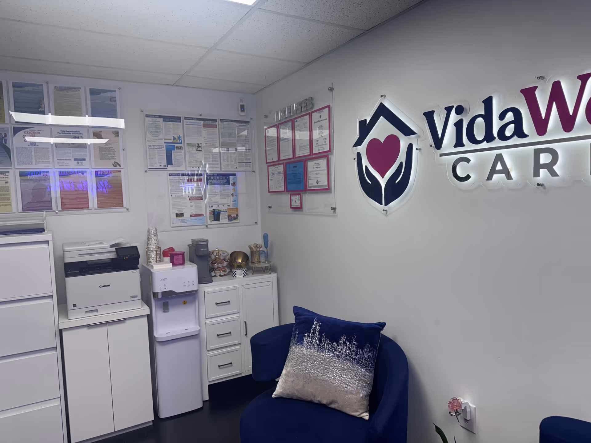 Interior lobby with VidaWell Care logo, blue chair, and office equipment.