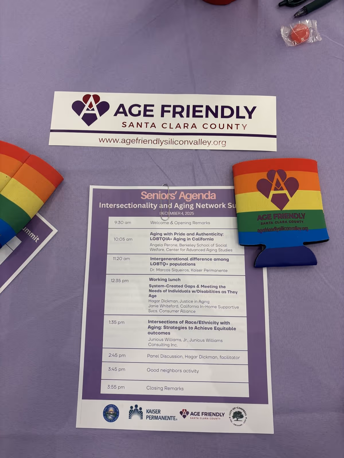Purple table with Age Friendly signage and a printed schedule at an event