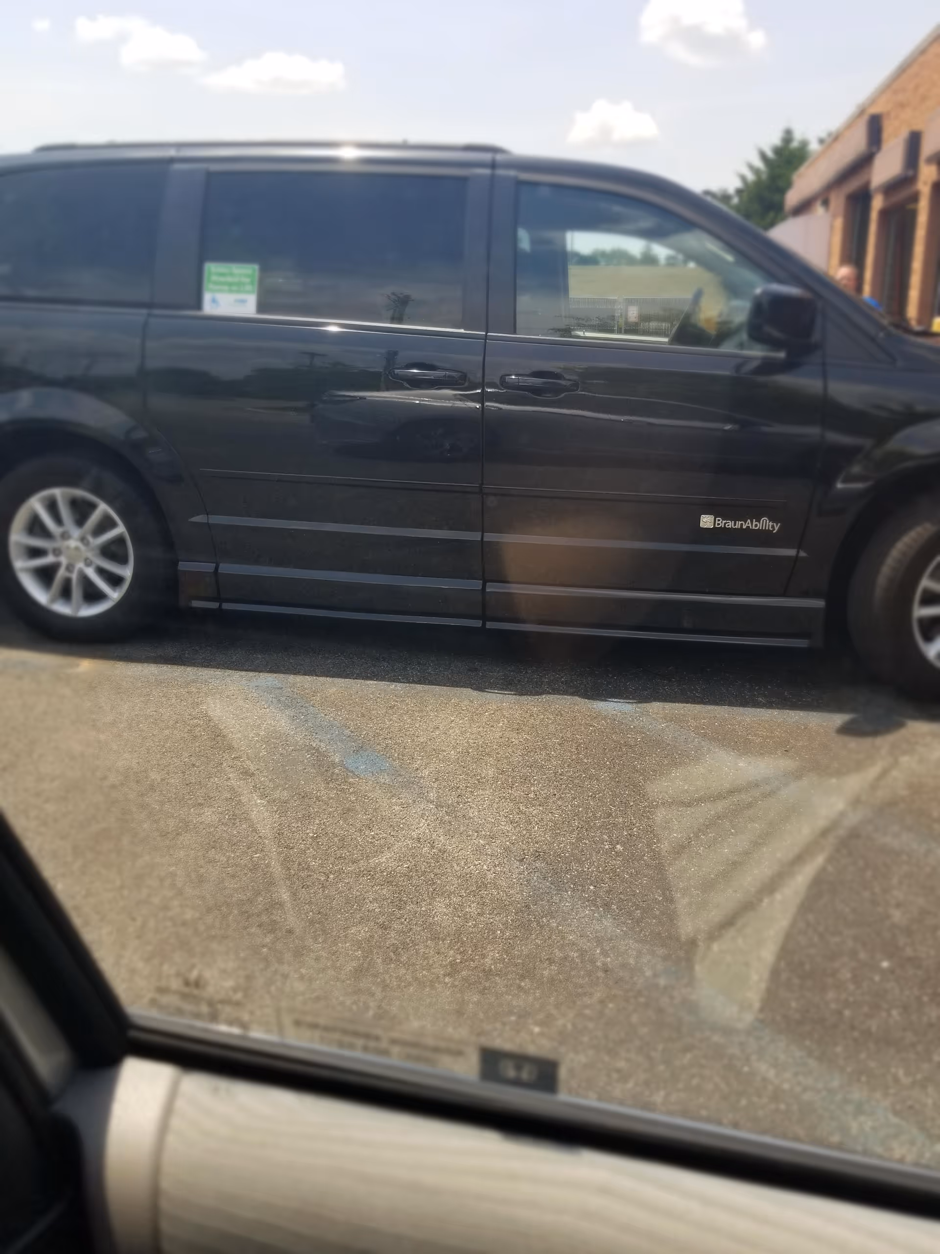 Dark wheelchair-accessible van with BraunAbility branding parked beside a building.