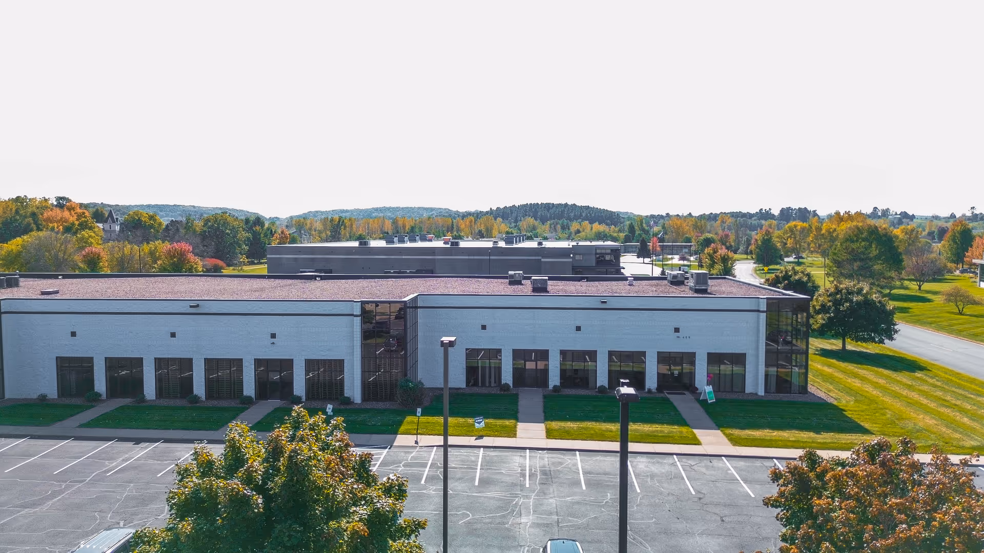 A single-story modern facility with glass entrance, parking lot, and green grounds.