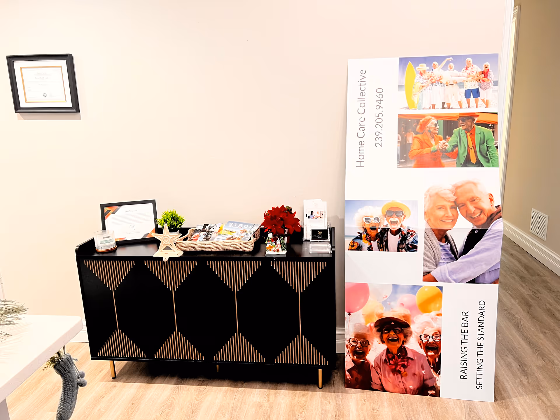 Reception area with a black geometric cabinet, magazines, and a tall Home Care Collective banner.