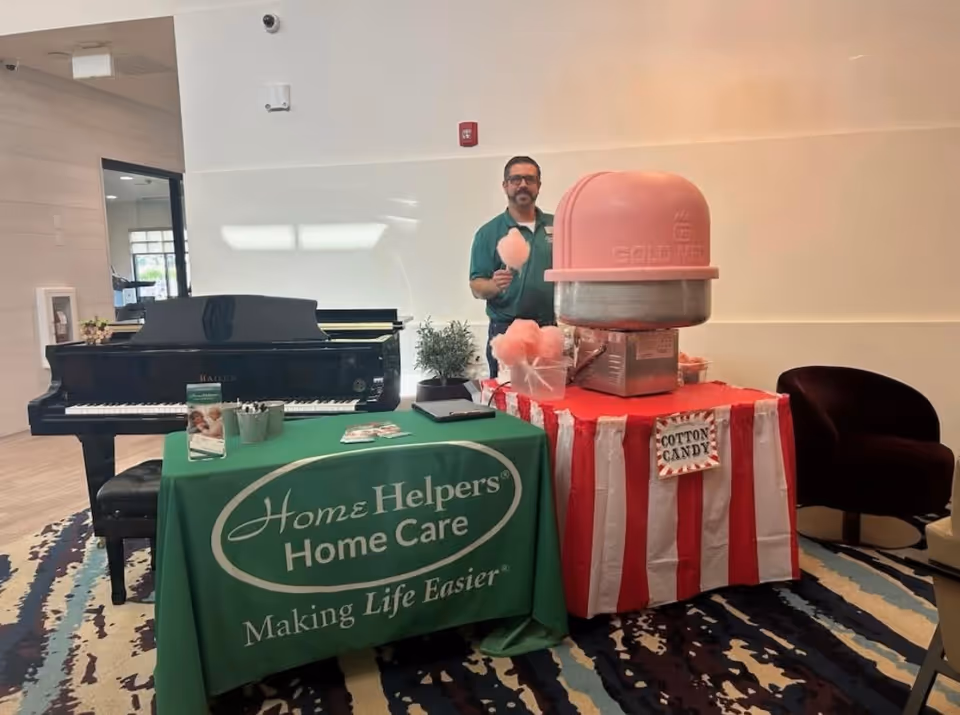 Staff member stands behind a Home Helpers care table beside a cotton candy machine.