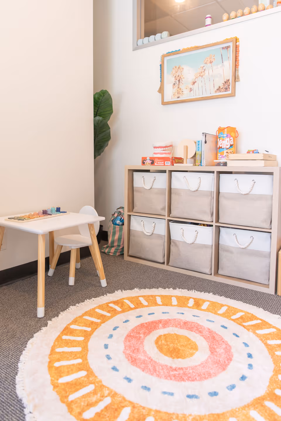 Cozy indoor play area with cubby storage, a small table, and a bright circular rug.