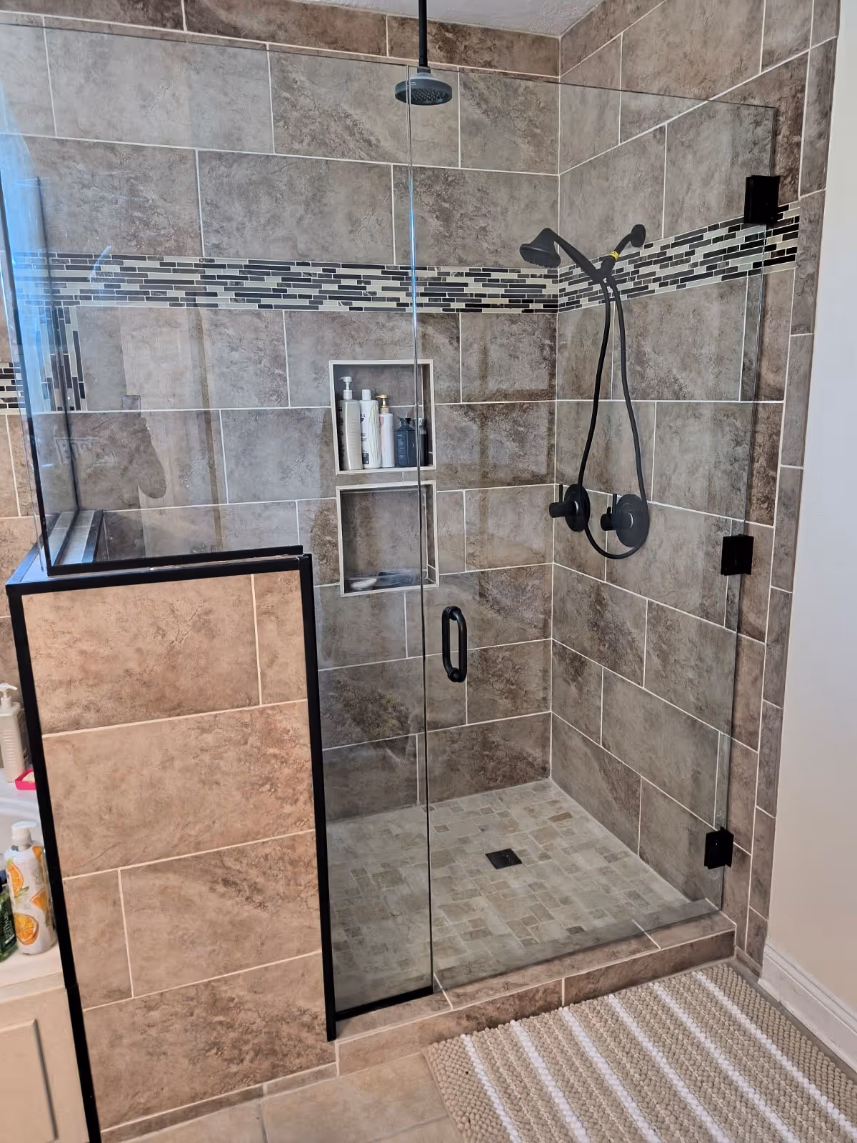Glass-walled tiled shower with built-in niches and multiple shower fixtures.