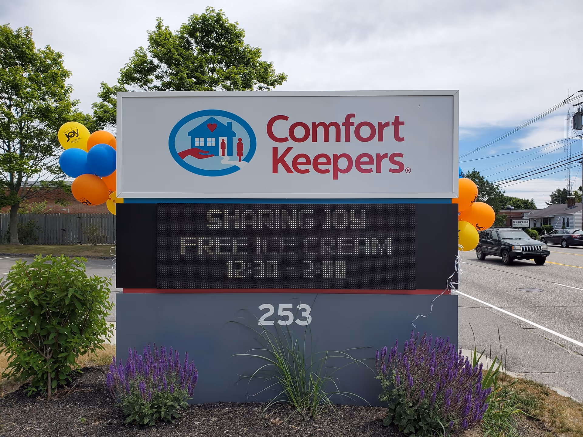 Outdoor Comfort Keepers sign with balloons at a roadside frontage
