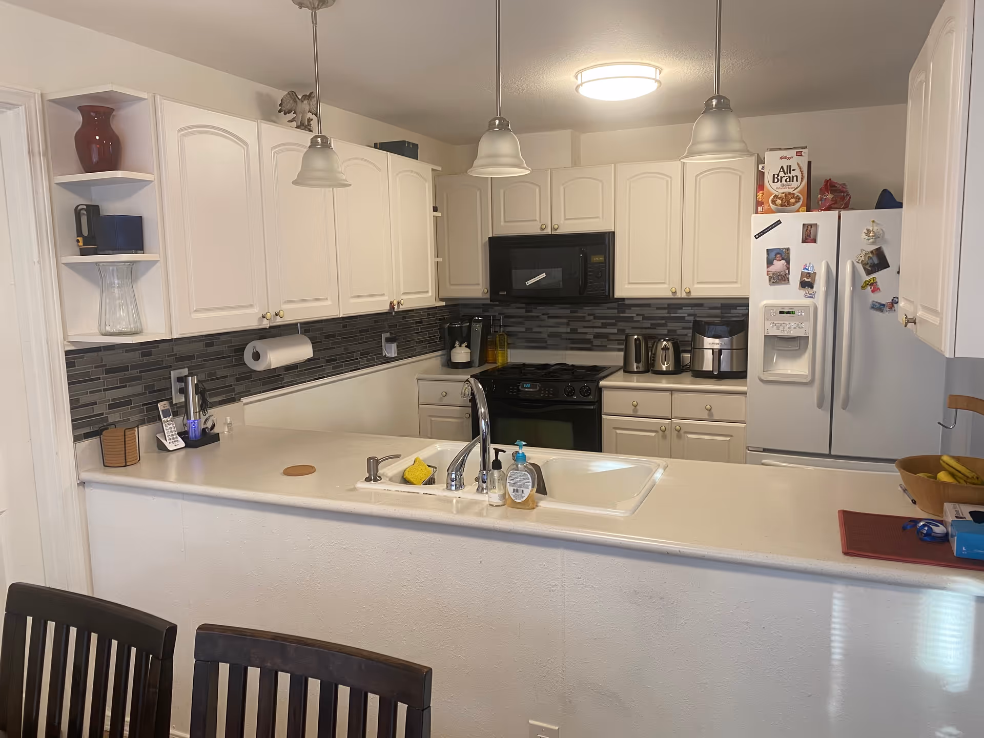 Bright white kitchen with island, cabinets, appliances, and pendant lights.