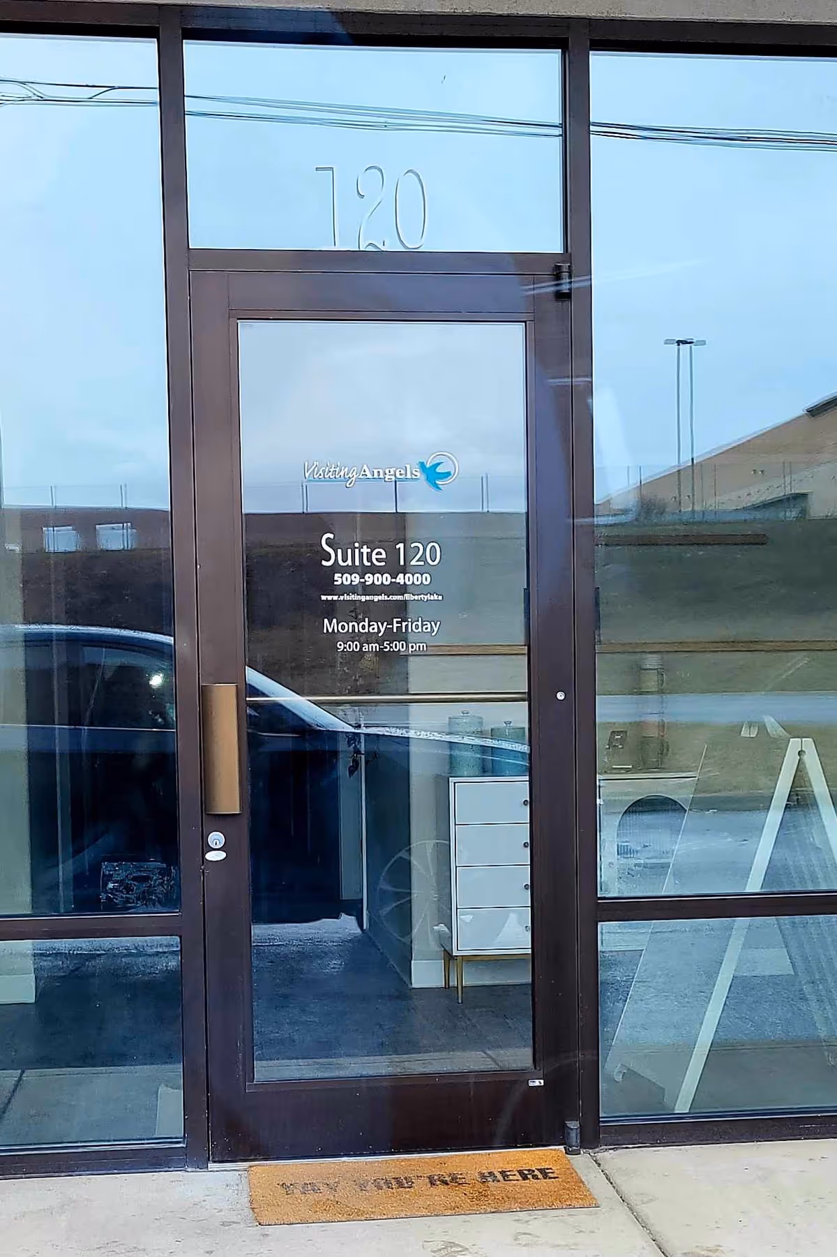Front entrance of Visiting Angels building with glass doors and Suite 120 signage.
