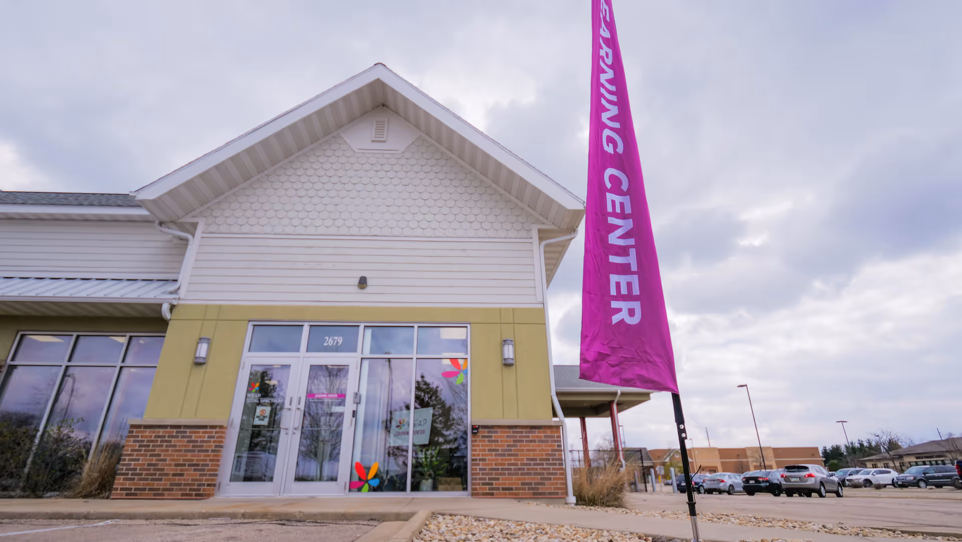 Exterior view of a modern clinic building with a pink vertical banner outside.