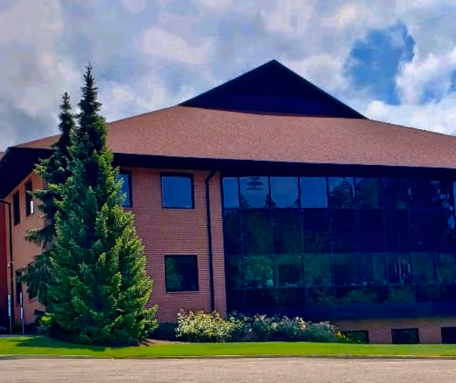 Modern brick health care building with large glass windows and green landscaping.
