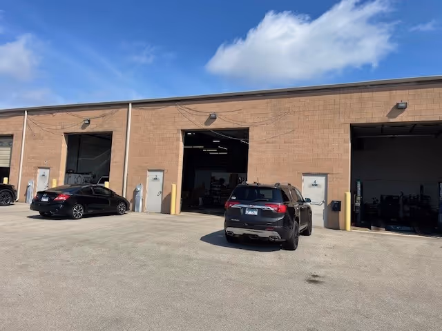 Exterior view of a MobilityWorks facility with open loading bays and parked cars.