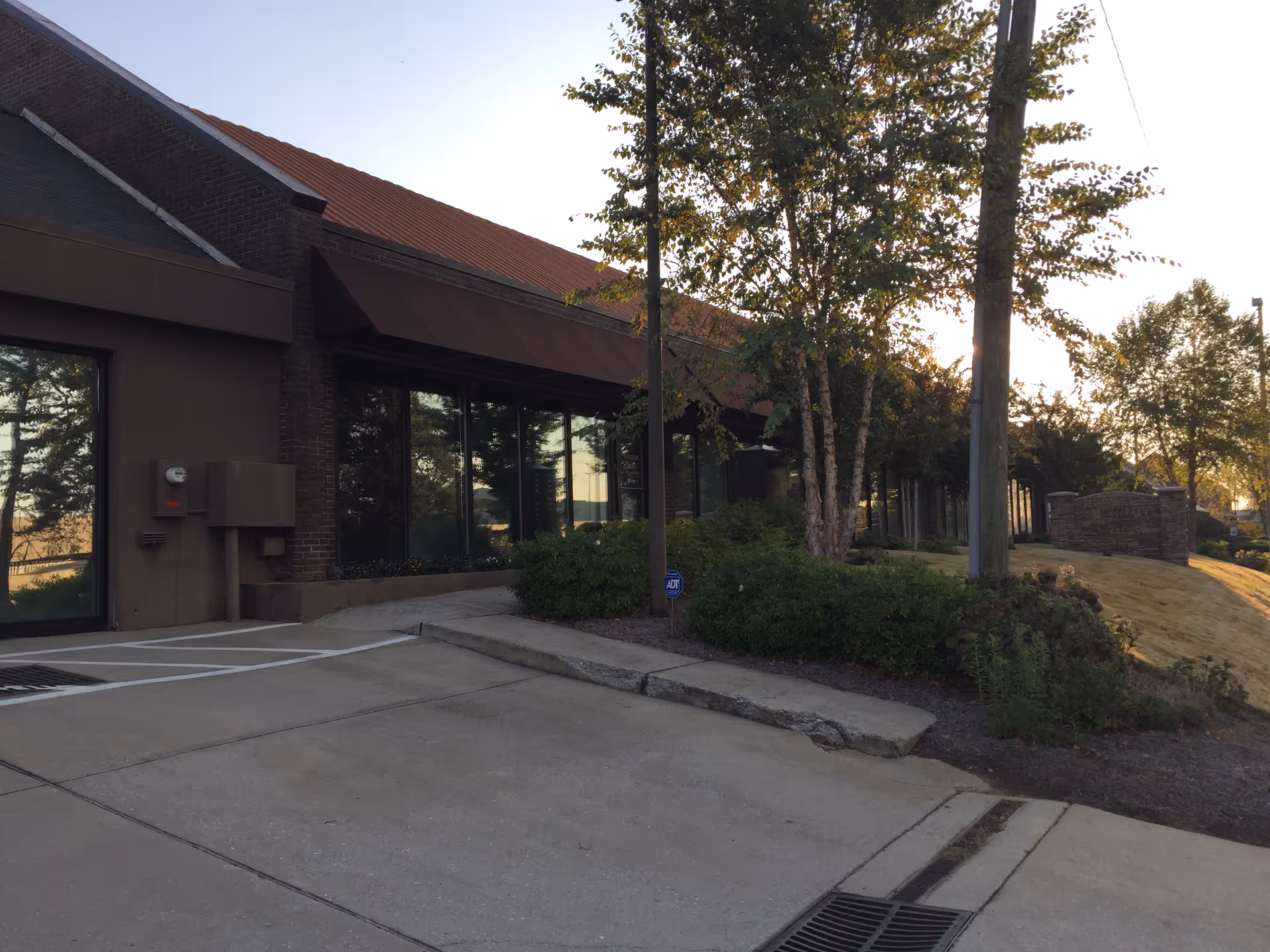 Exterior view of a building with glass storefront windows and landscaped front area.