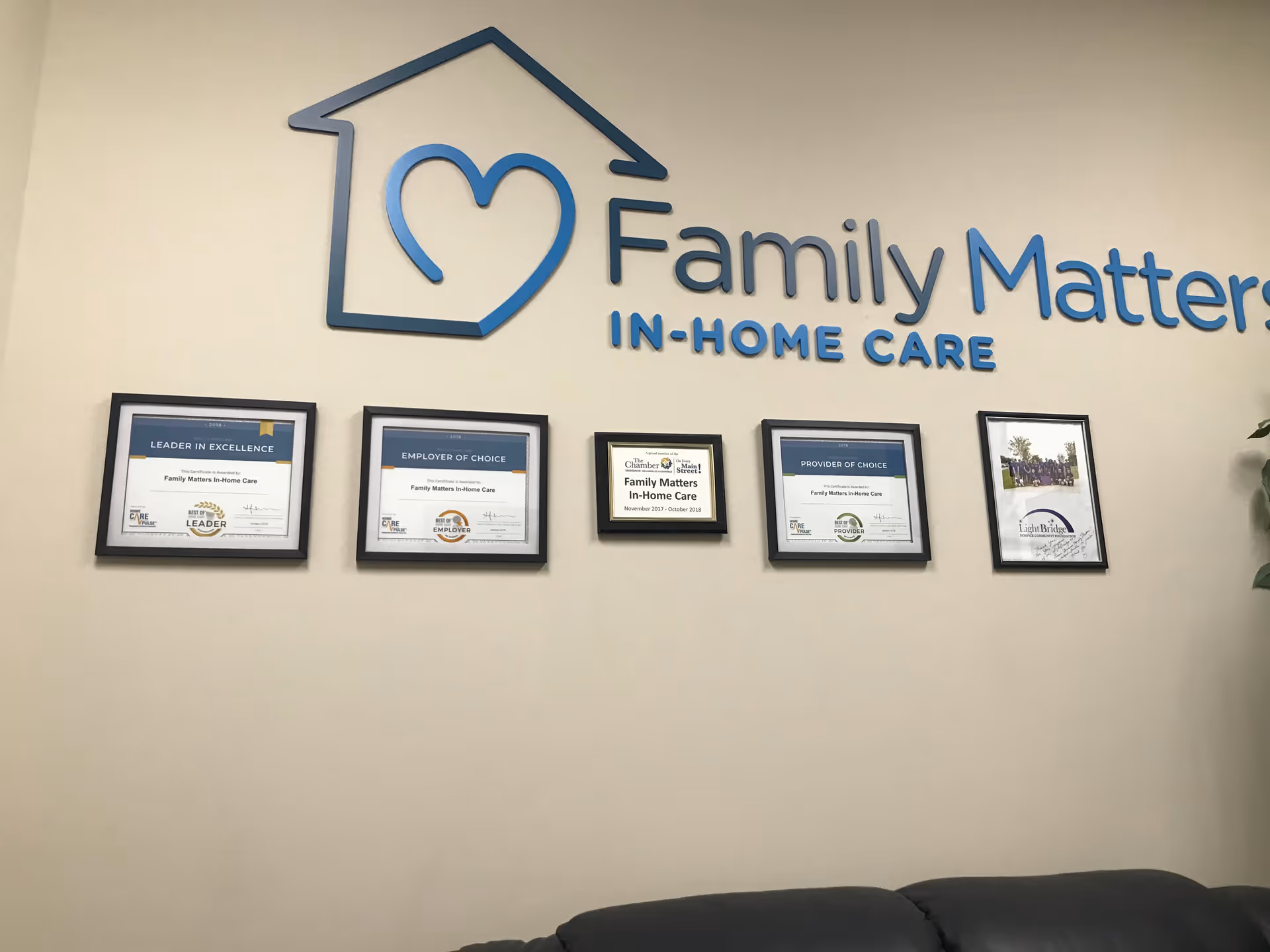 Interior wall with Family Matters In-Home Care logo and framed certificates above a couch.