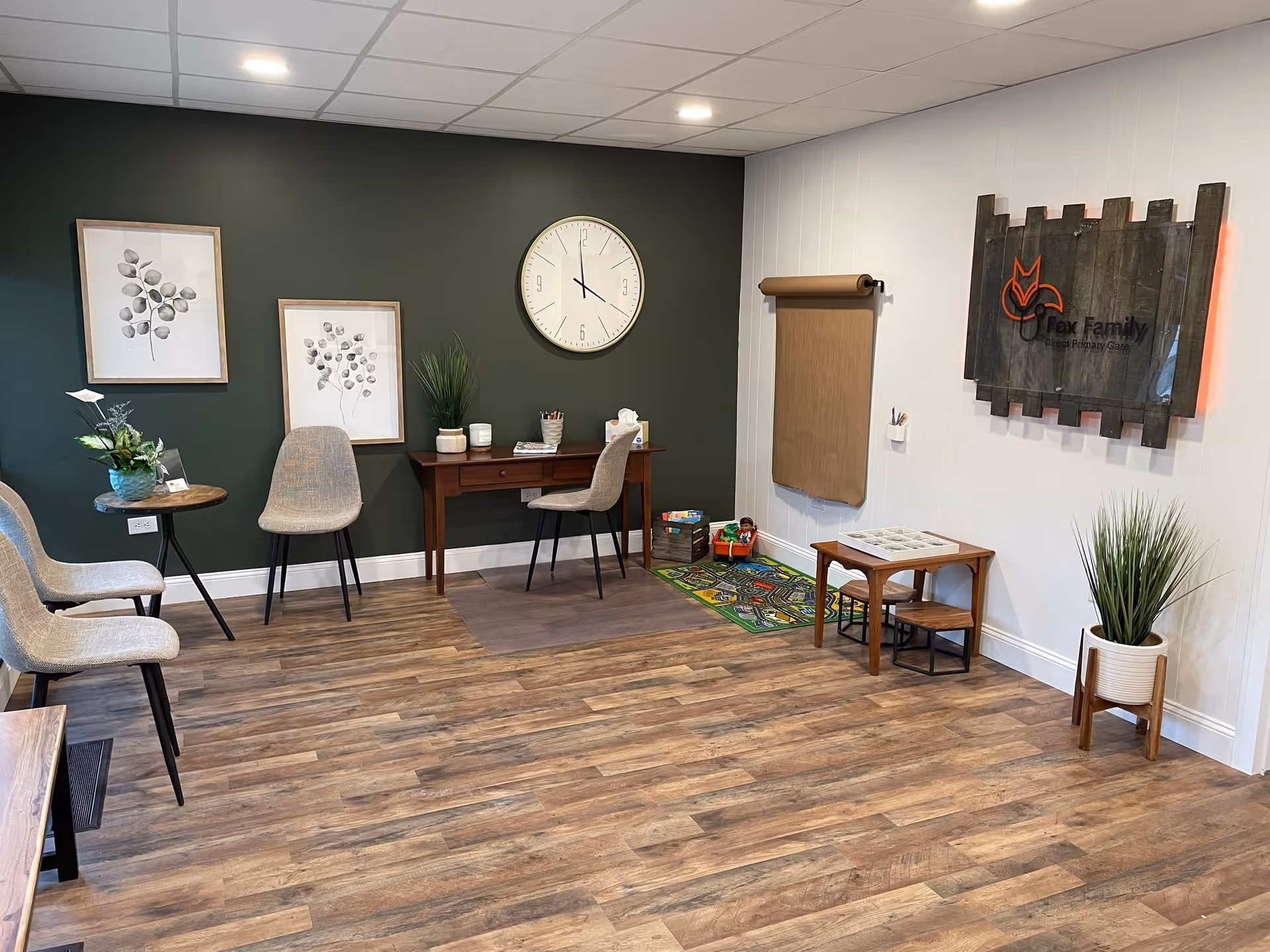 A quiet interior waiting area with chairs, a desk, clock, plants, and Fox Family sign.