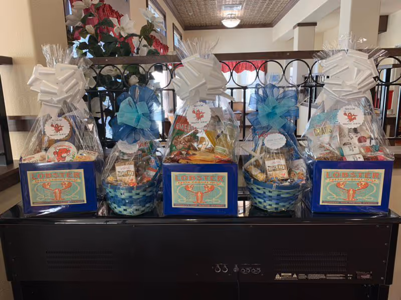 Three gift baskets wrapped in cellophane sit atop a dark console in a hallway.