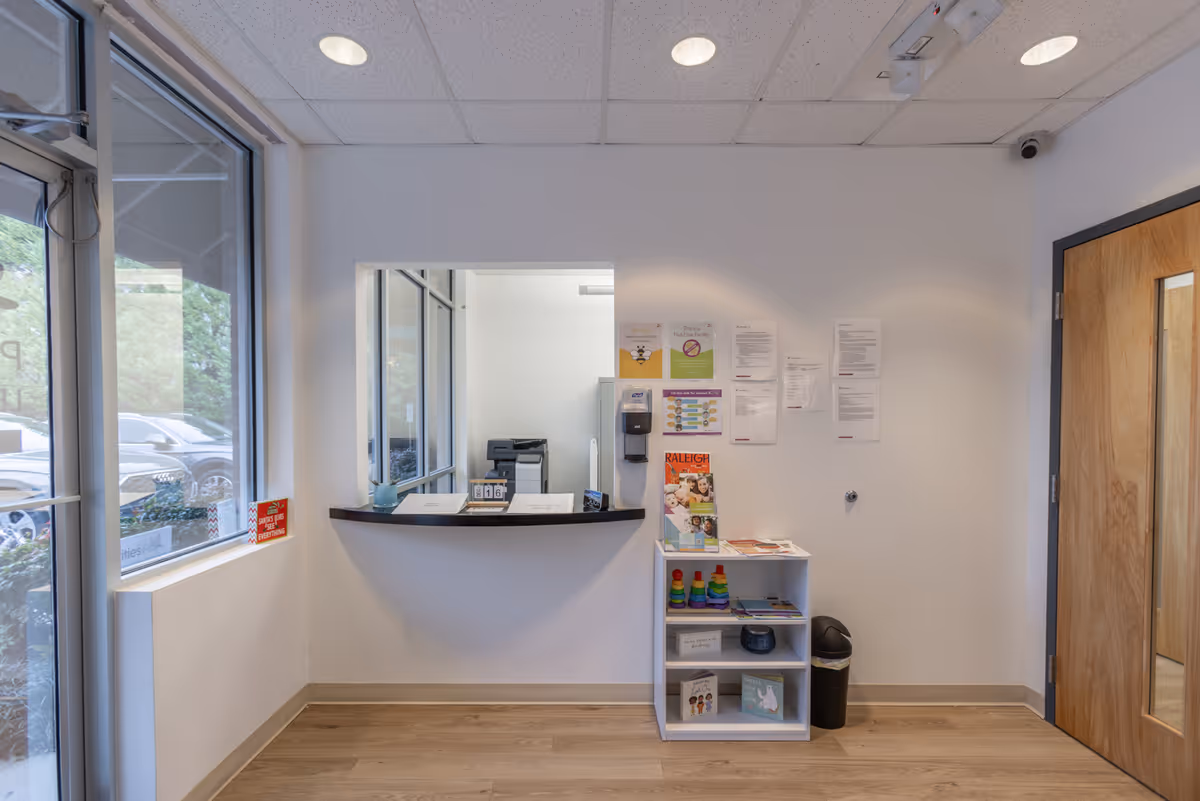 Interior reception area with curved front desk, window, and pamphlet shelf.