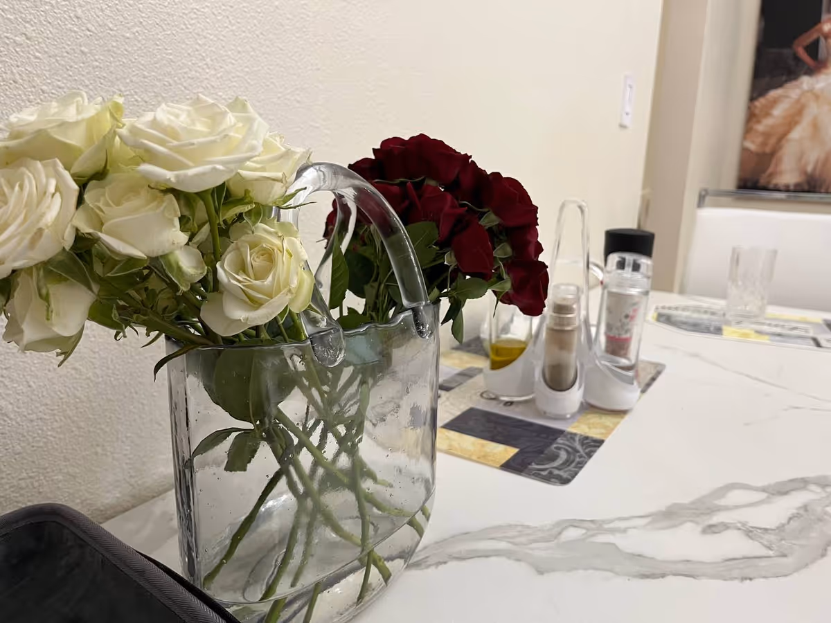 Glass vase with white and red roses on a marble dining table.