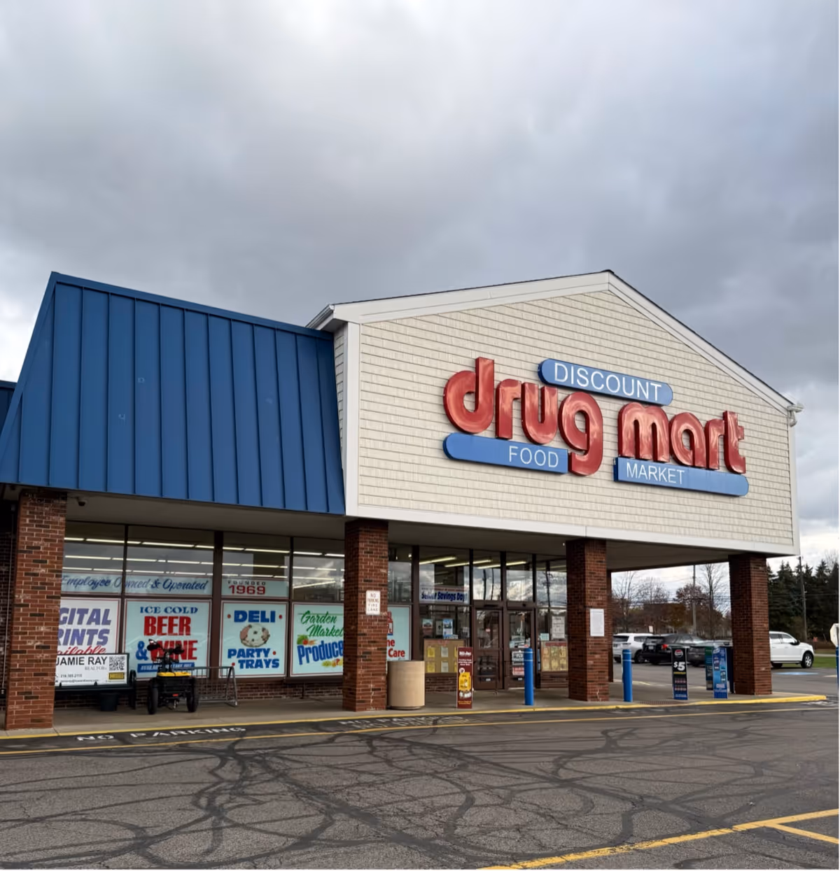 Front exterior of Discount Drug Mart storefront with blue roof and brick columns.