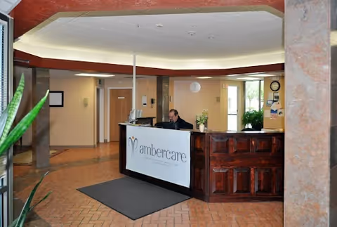 Ambercare reception lobby with a wooden front desk and staff at work.