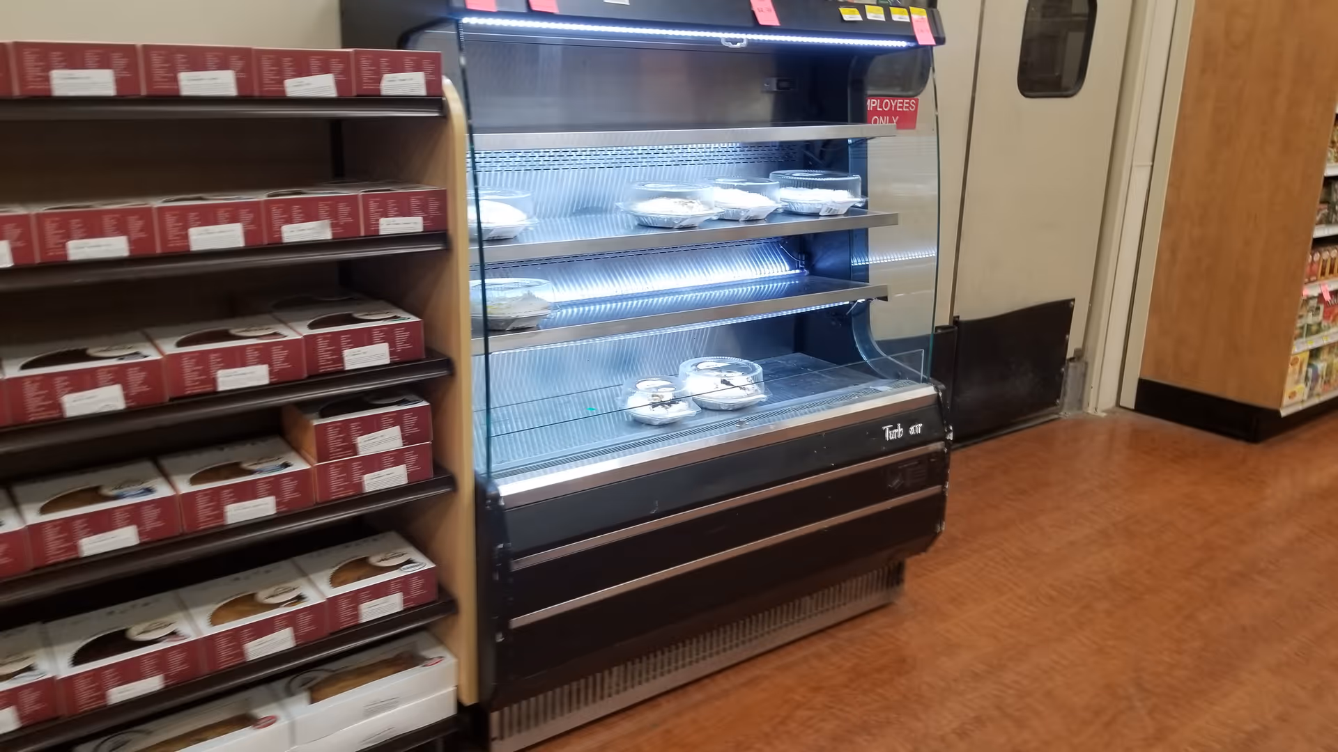 Interior store aisle with a glass display case and stacked red boxes.