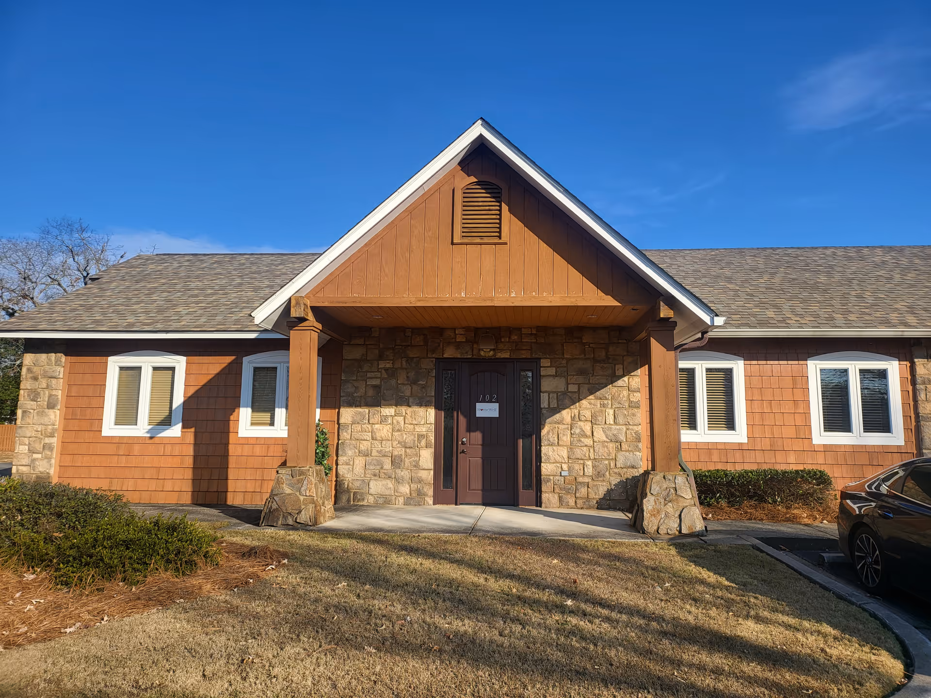 Single-story senior housing building with stone façade and covered front entrance under blue sky.