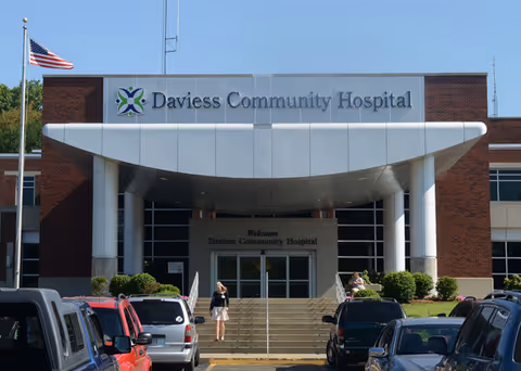 Front view of Daviess Community Hospital entrance with columns and parked cars.