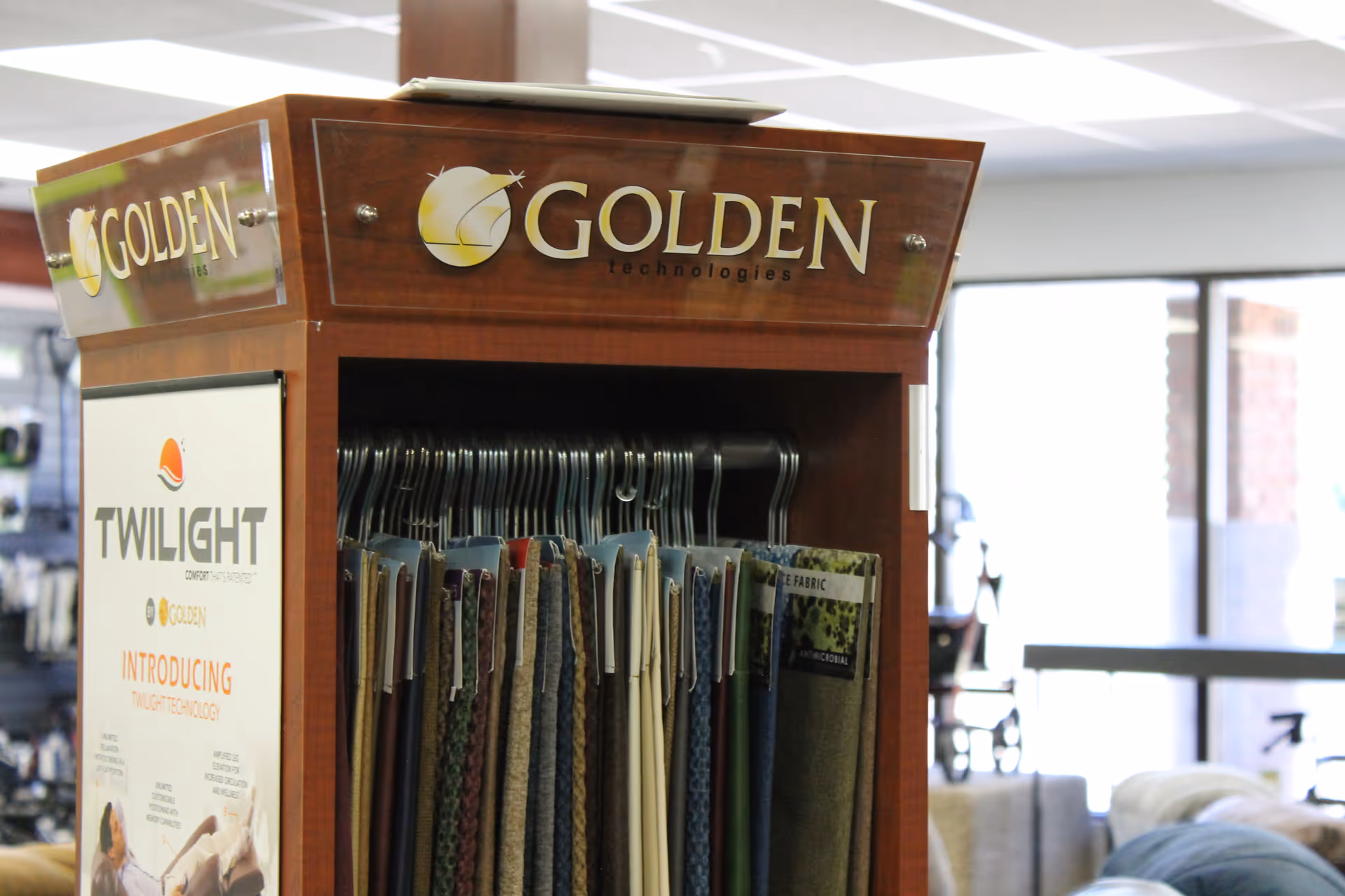 Wooden display rack with fabric swatches and Golden Technologies signage inside a showroom.