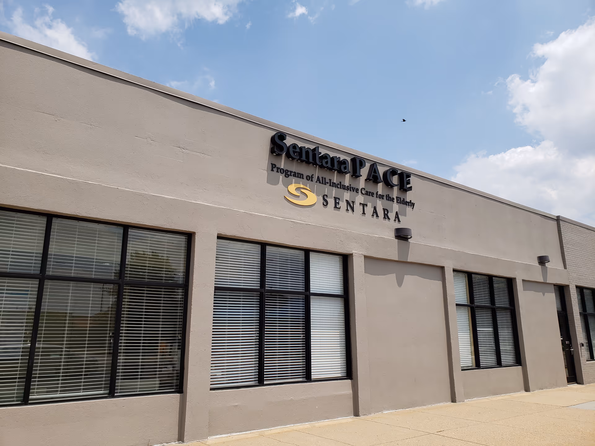 Exterior view of Sentara PACE facility with tan walls and large windows.