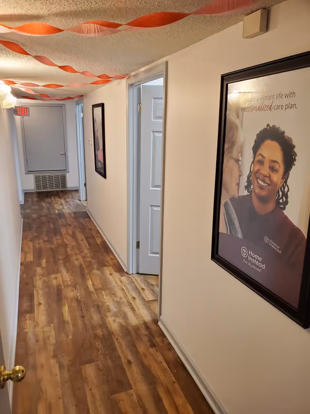 Narrow hallway in a senior living facility with orange streamers and wall posters.