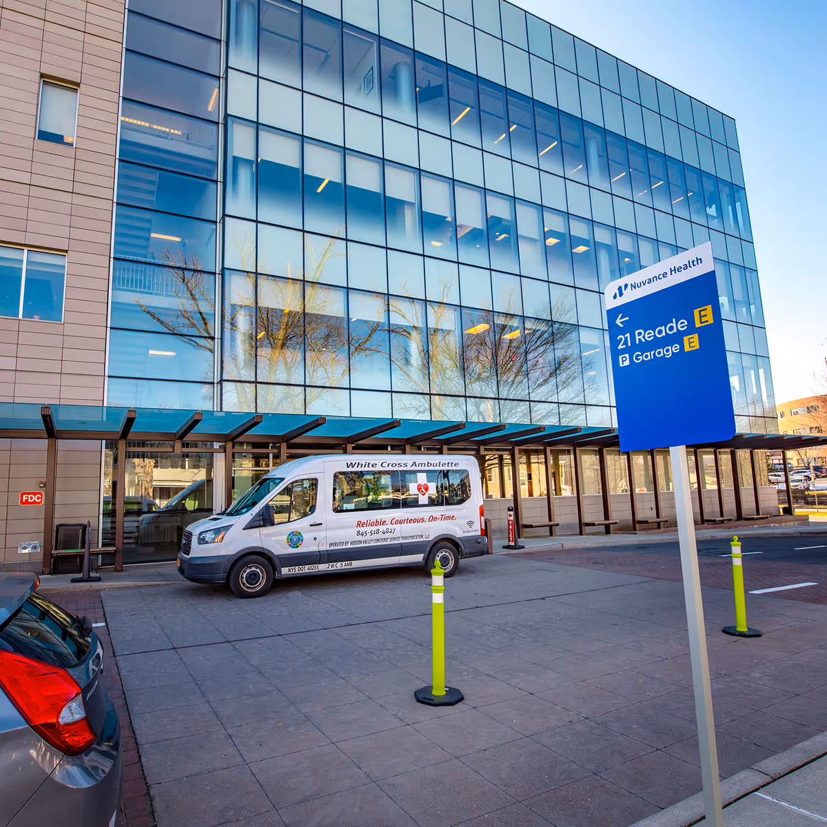 Modern glass-front medical center exterior with a white van parked near the entrance.