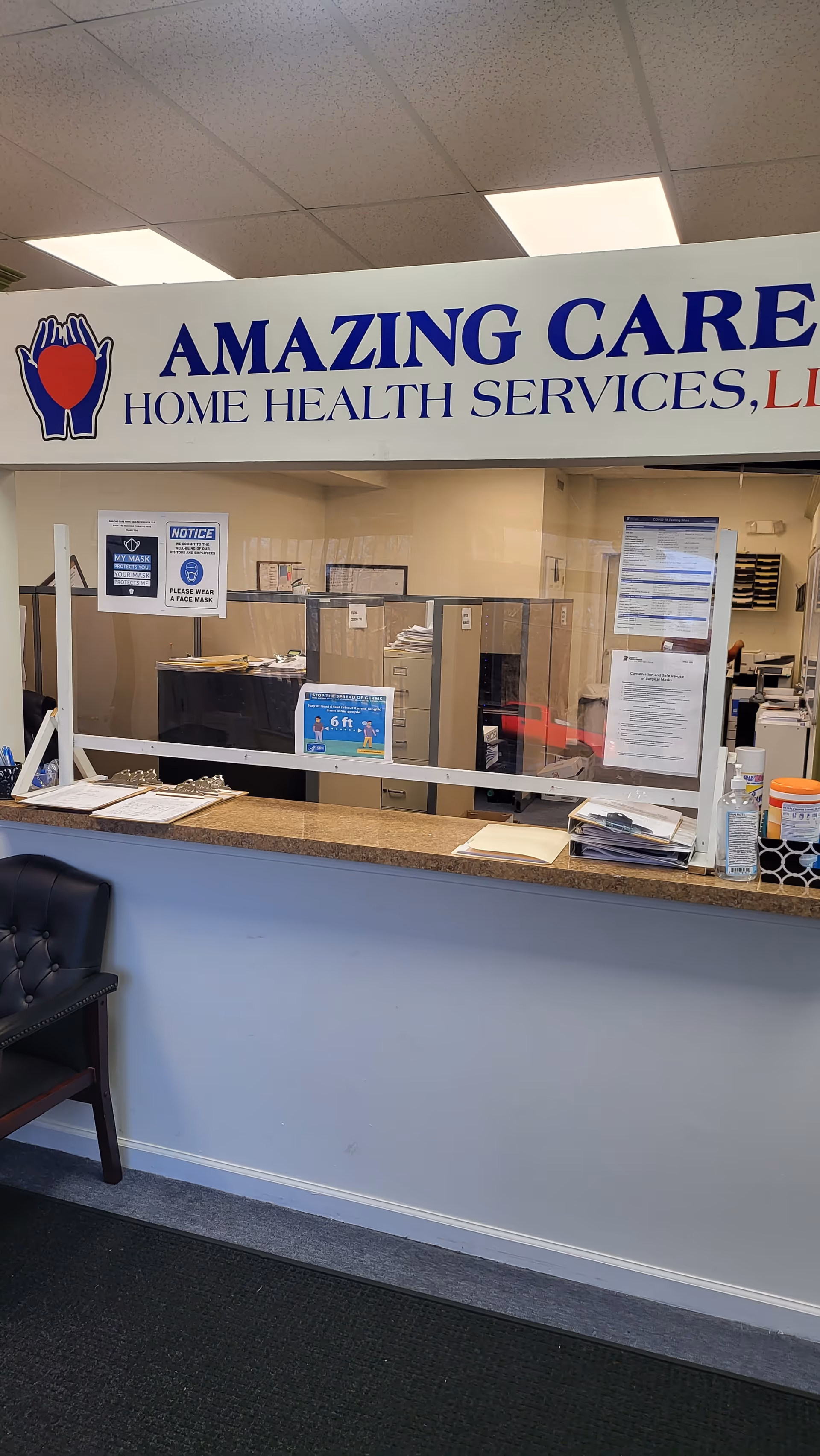 Indoor reception area with a counter, glass divider, and an 'Amazing Care Home Health Services' sign.