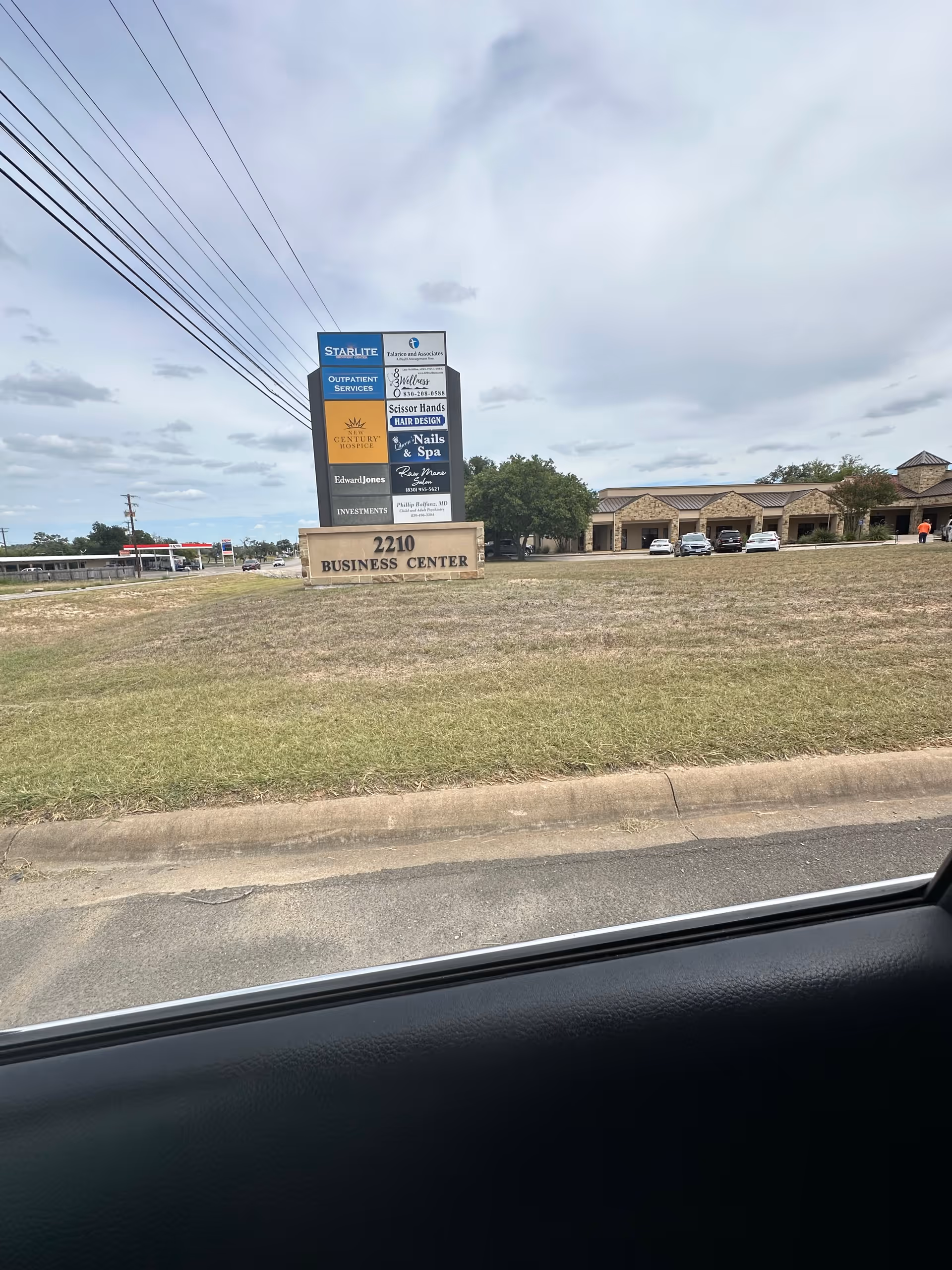Exterior view of a business center with a tall multi-tenant sign near the road