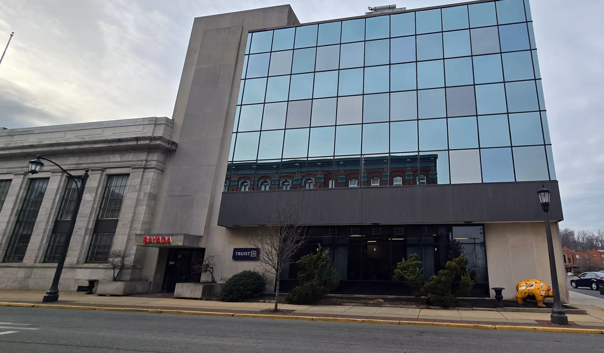 Modern glass-front building labeled BAYADA Hospice along a city street.
