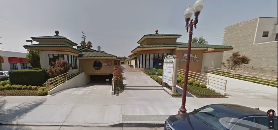 Front view of a beige Asian-inspired senior living facility with a driveway and ramp.
