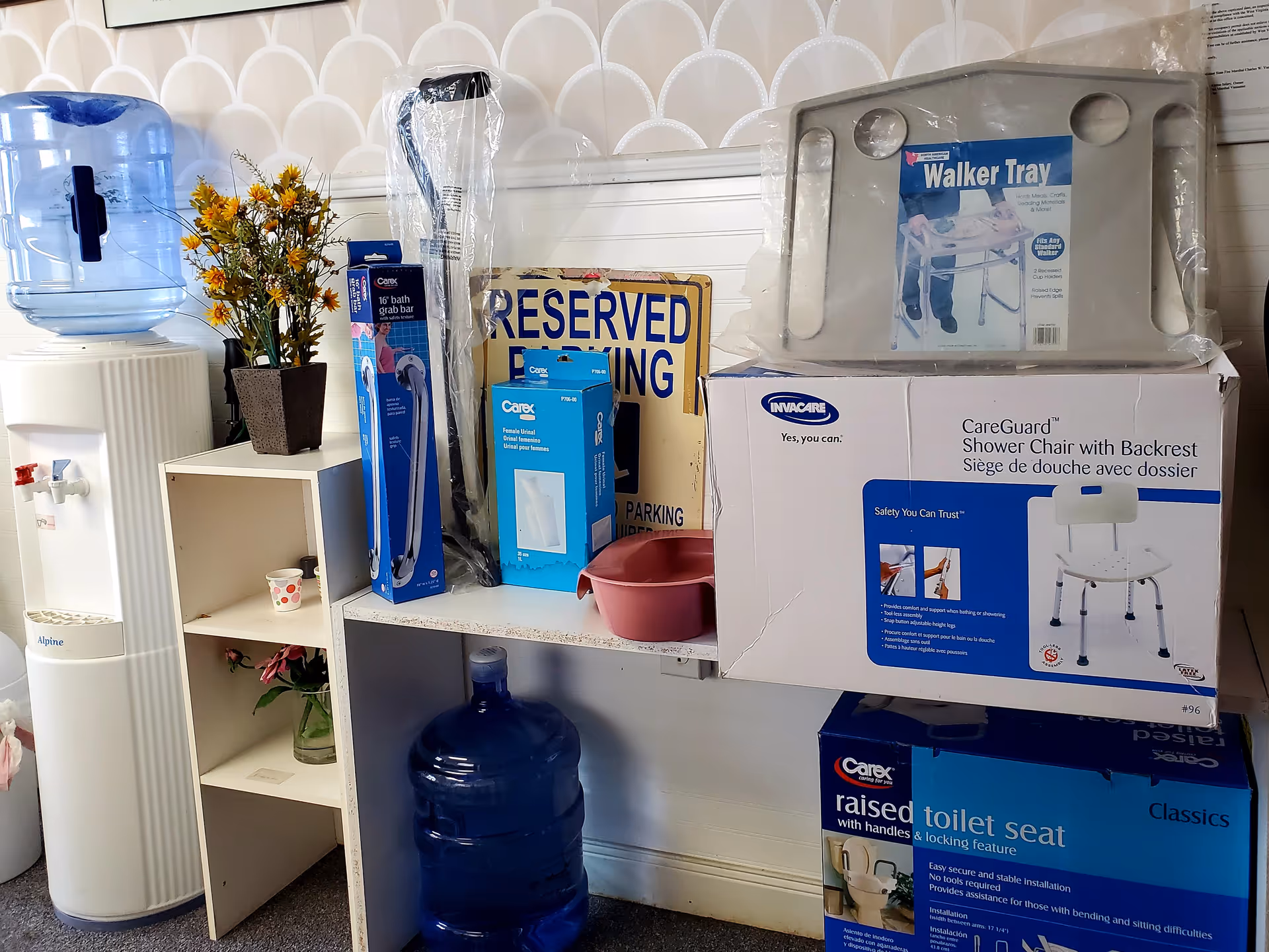 Interior area with water dispenser, plant, and boxed medical equipment on shelves