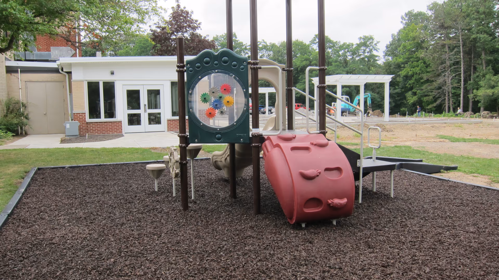 Outdoor playground equipment near a brick building with glass doors at a senior facility.