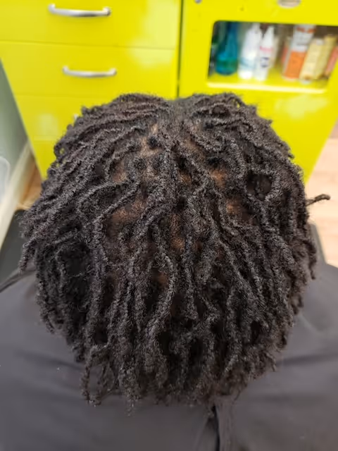 Top-down view of a person with dreadlocks in front of a yellow salon cabinet.
