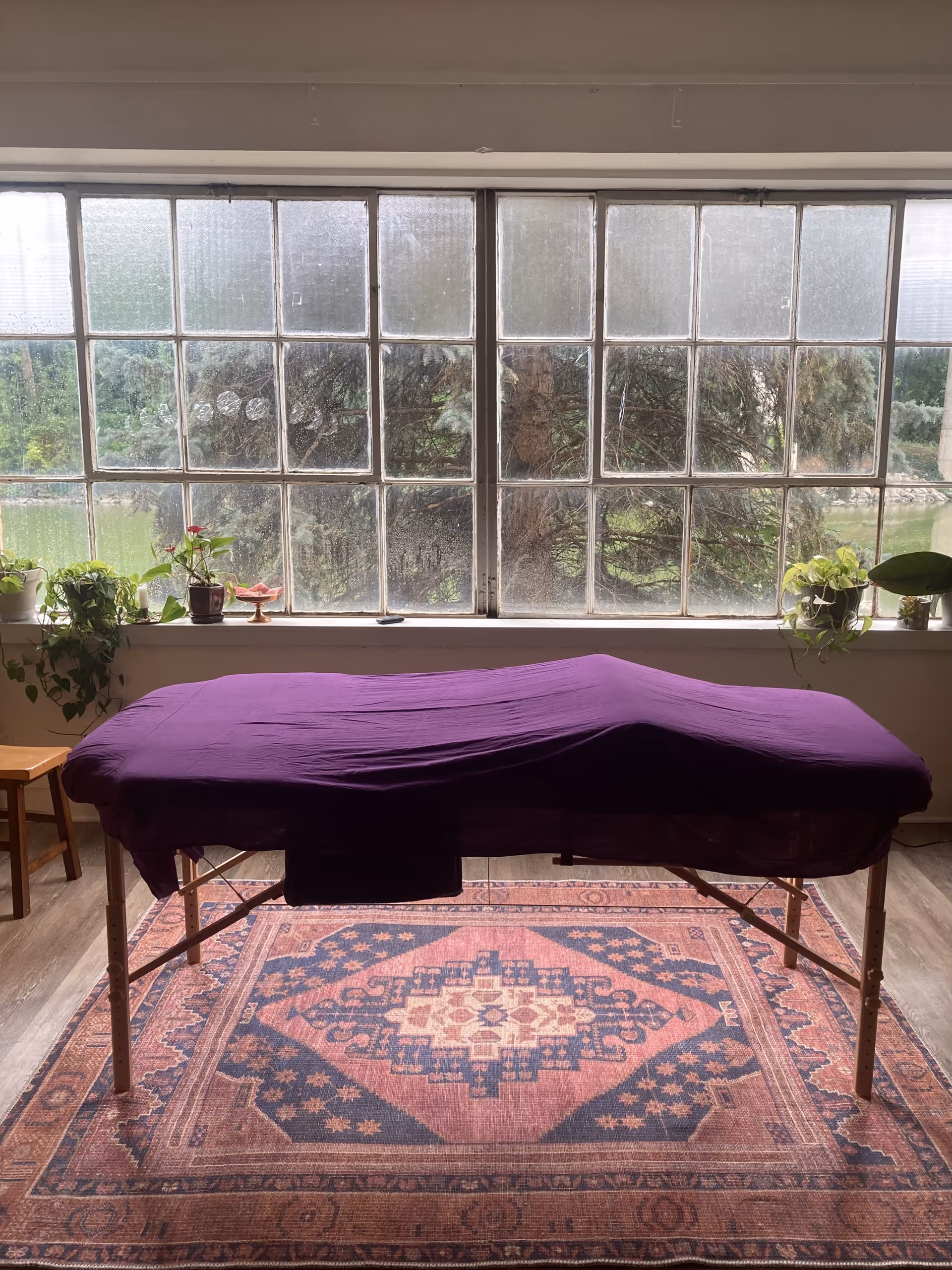 Massage table with purple cover in a bright room with a large window