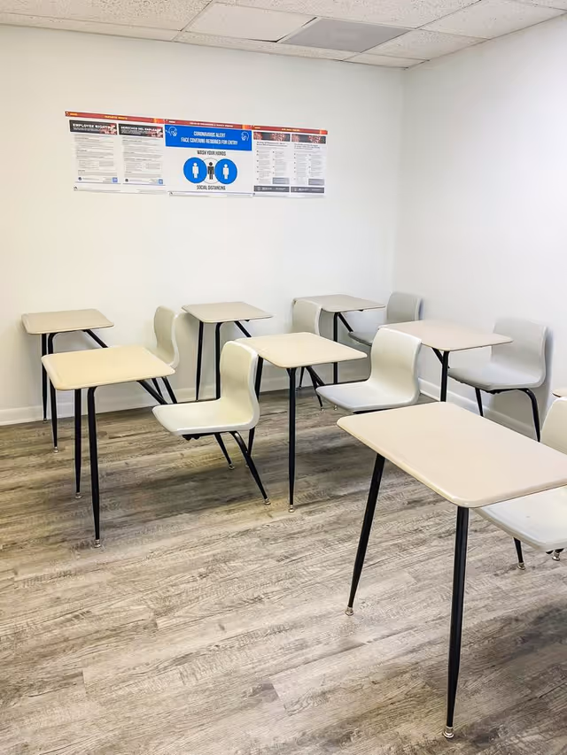 A small classroom inside a senior facility with desks, chairs, and wall posters.